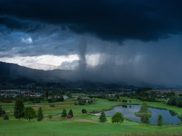 Regenwolken über grünen Wiesen.
