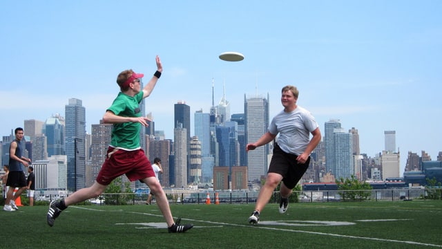 Zwei Frisbee-Spieler vor der New Yorker Skyline