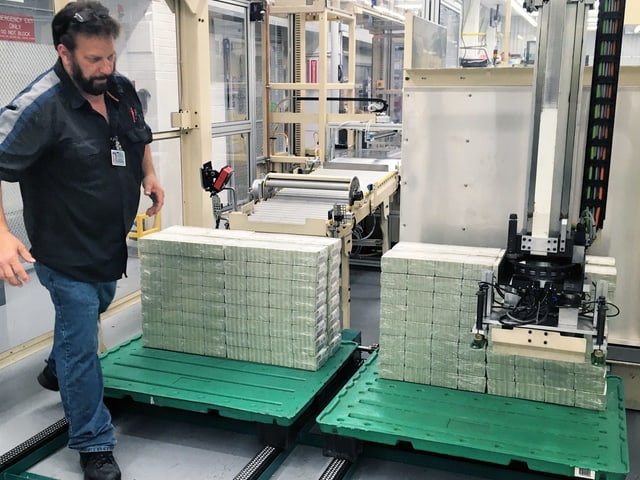 Im Bureau of Engraving and Printing: ein Mitarbeiter läuft an Geldstapeln vorbei. Im Bureau of Engraving and Printing: ein Mitarbeiter läuft an Geldstapeln vorbei.