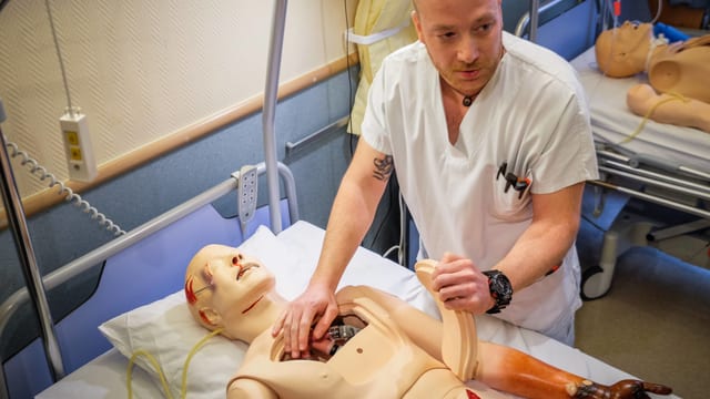 Mann hantiert mit Medizinpuppe Mann hantiert mit Medizinpuppe