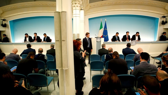 Drei Männer in Anzügen an einer Pressekonferenz Drei Männer in Anzügen an einer Pressekonferenz
