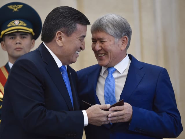 Ex-Präsident Atambajew (rechts) und sein Nachfolger Sooronbaj Scheenbekow reichen sich lächelnd die Hand.