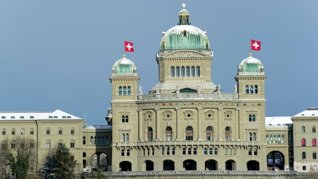 Das Bundeshaus mit wehenden Schweizer Fahnen und schneebedeckten Kuppeln. Das Bundeshaus mit wehenden Schweizer Fahnen und schneebedeckten Kuppeln.
