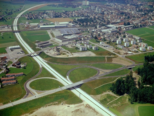 Auf einer Luftaufnahme sieht nam ein Autobahnkreuz neben einer Stadt.