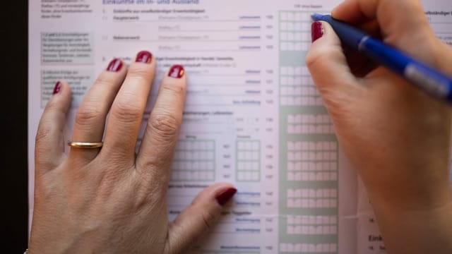 Eine Frau füllt eine Steuererklärung aus. Eine Frau füllt eine Steuererklärung aus.