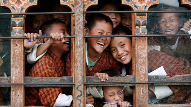 Schülen schauen lachend aus den Fenstern eines Klassenzimmers