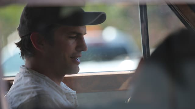 Ein Mann mit Basecap sitzt in einem Auto. Ein Mann mit Basecap sitzt in einem Auto.