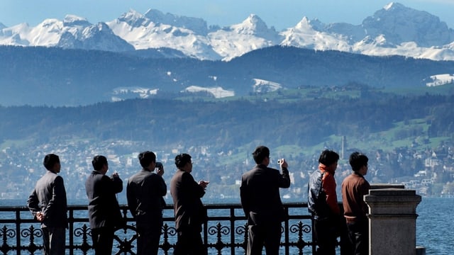 Touristen stehen auf einem Aussichtspunkt und fotografieren das Panorama Touristen stehen auf einem Aussichtspunkt und fotografieren das Panorama
