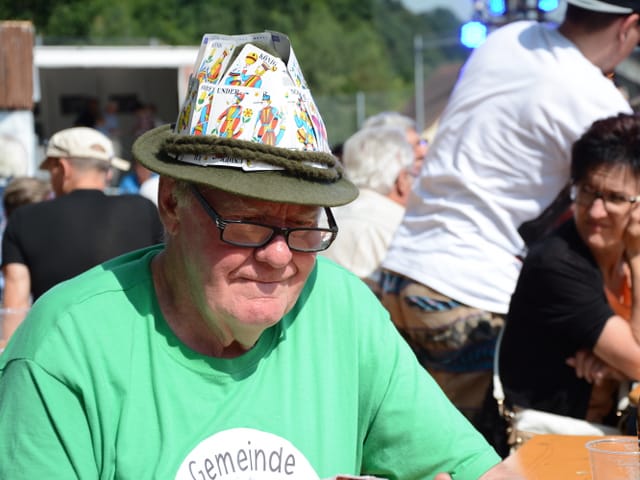 Mann mit Jasskarten am Hut.