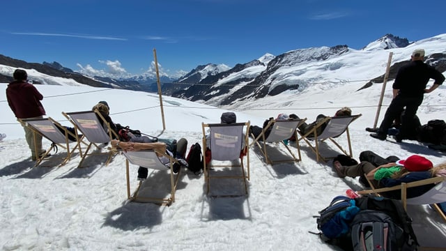 Leute liegen in Liegestühlen im Schnee. Leute liegen in Liegestühlen im Schnee.
