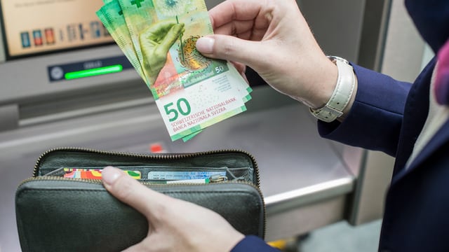 Jemand legt neue 50er-Scheine aus einem Bankomaten in eine Brieftasche, Jemand legt neue 50er-Scheine aus einem Bankomaten in eine Brieftasche,