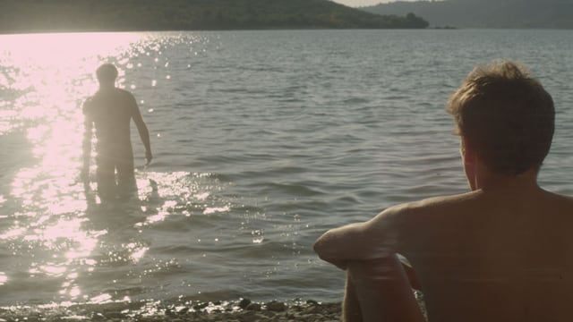 Mann am Strand schaut anderem Mann bei Baden zu. Mann am Strand schaut anderem Mann bei Baden zu.