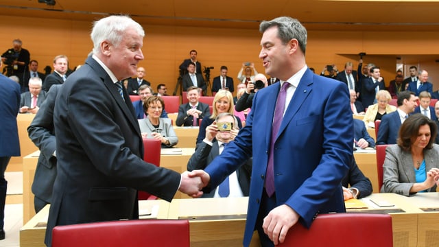 Seehofer und Söder geben sich im bayrischen Parlament die Hand. Seehofer und Söder geben sich im bayrischen Parlament die Hand.
