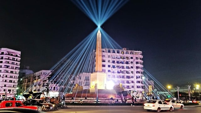 Platz mit grossem Obelisk, der mit zahlrechen Schweinwerfern beleuchtet wird Platz mit grossem Obelisk, der mit zahlrechen Schweinwerfern beleuchtet wird