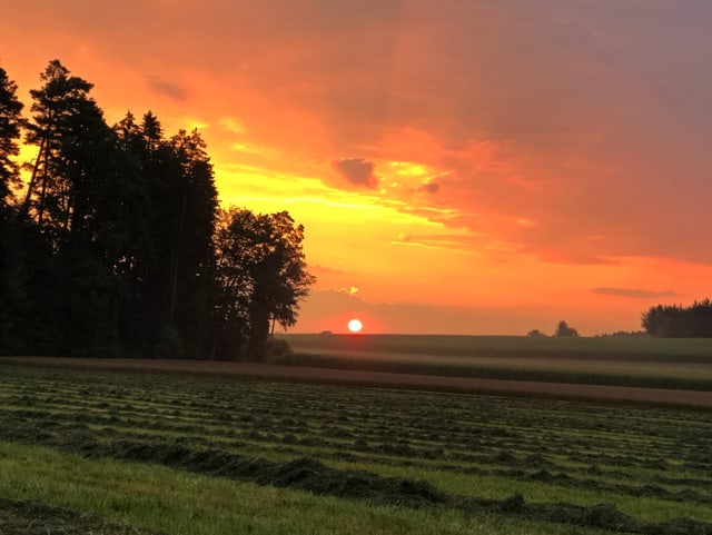 Die aufgehende Sonne lässt die Wolkenreste rötlich erscheinen.