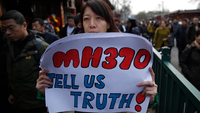 Eine Frau hält ein Transparent mit der Aufschrift «MH370, tell us truth!» Eine Frau hält ein Transparent mit der Aufschrift «MH370, tell us truth!»