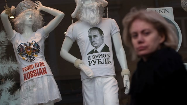 Frau vor einem Schaufenster, zwei Schaufensterpuppen mit «proud to be russian»-Shirts. Frau vor einem Schaufenster, zwei Schaufensterpuppen mit «proud to be russian»-Shirts.