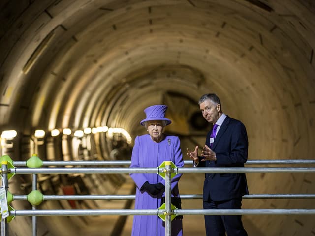 Die Queen in einer Untergrundbahnröhre stehend.