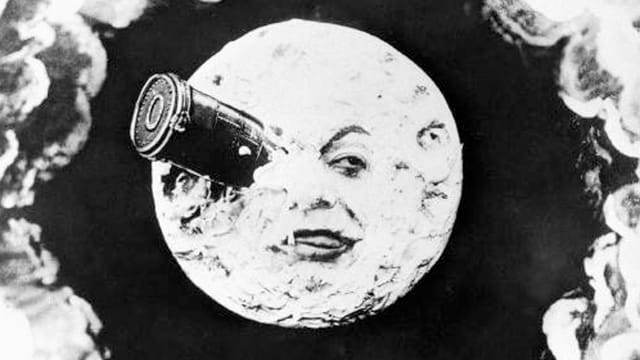Schwarz-Weiss-Bild: Ein Mond mit einem Gesicht. Ein Auge ist von einem Fernrohr bedeckt. Schwarz-Weiss-Bild: Ein Mond mit einem Gesicht. Ein Auge ist von einem Fernrohr bedeckt.