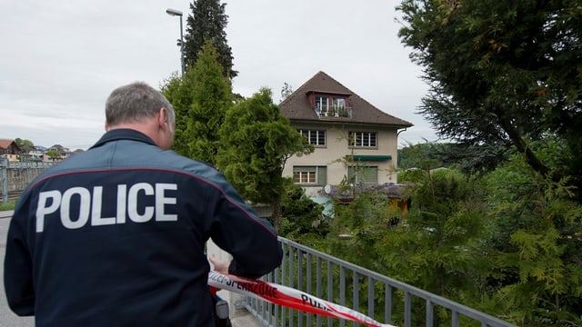 Polizist vor einem Haus Polizist vor einem Haus