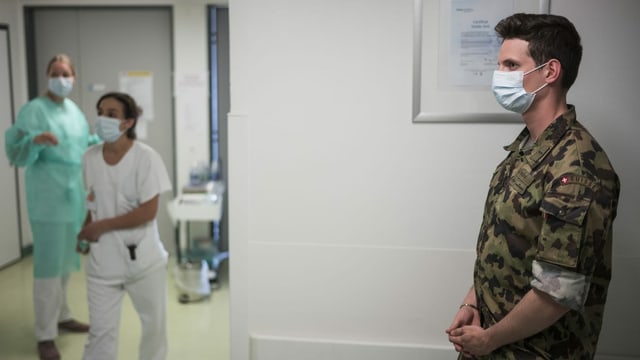 Ein Soldat mit Gesichtsmaske steht in einem Spitalgang.