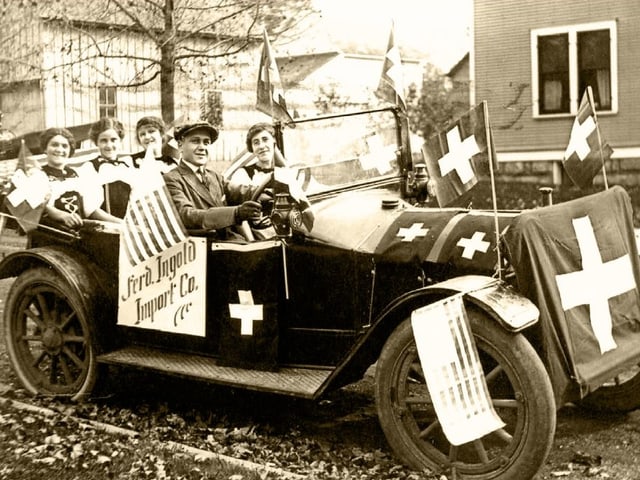 Ein Archivbild: Personen in einem alten Auto mit Schweizer Flaggen Ein Archivbild: Personen in einem alten Auto mit Schweizer Flaggen