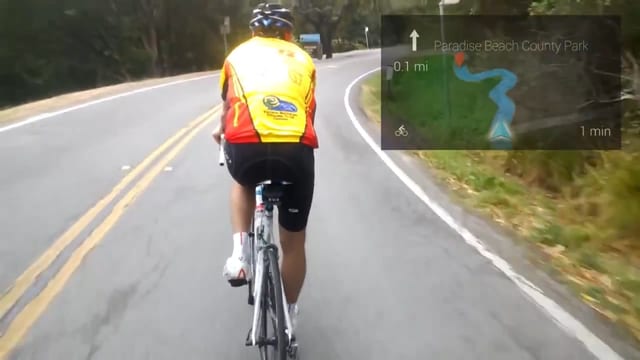 Blick durch ein Google Glass: Eine Strasse mit Radfahrer, in der oberen rechten Ecke wird eine Strassenkarte eingeblendet Blick durch ein Google Glass: Eine Strasse mit Radfahrer, in der oberen rechten Ecke wird eine Strassenkarte eingeblendet