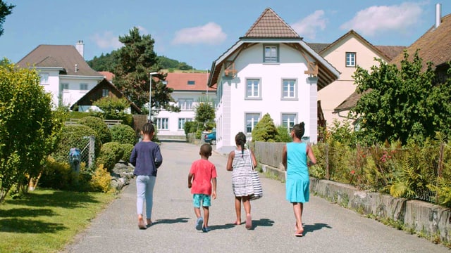 4 schwarze Menschen gehen eine Quartierstrasse entlang. 4 schwarze Menschen gehen eine Quartierstrasse entlang.