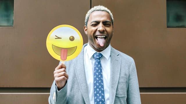 Mann mit ausgestreckter Zunge hält grosses Emoji mit ausgestreckter Zunge