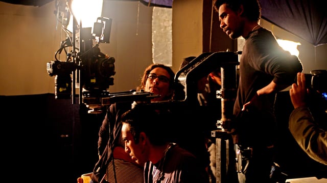 Hala Elkoussy sitzt hinter der Kamera bei einem Filmdreh, neben ihr sind zwei Mitarbeiter, die konzentriert bei der Arbeit sind. Hala Elkoussy sitzt hinter der Kamera bei einem Filmdreh, neben ihr sind zwei Mitarbeiter, die konzentriert bei der Arbeit sind.