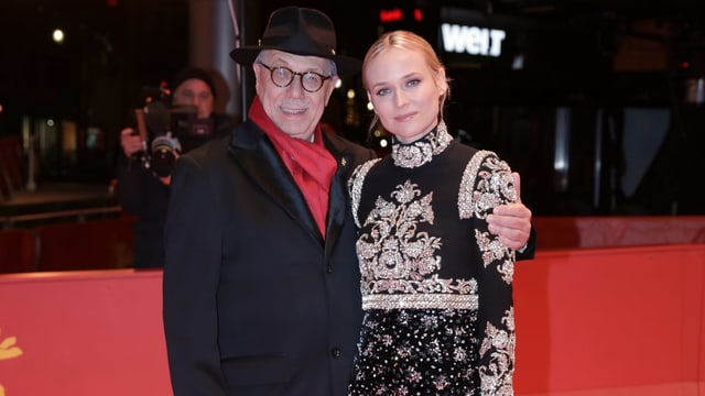 Ein Mann mit Hut hält eine elegante Frau im Abendkleid Ein Mann mit Hut hält eine elegante Frau im Abendkleid