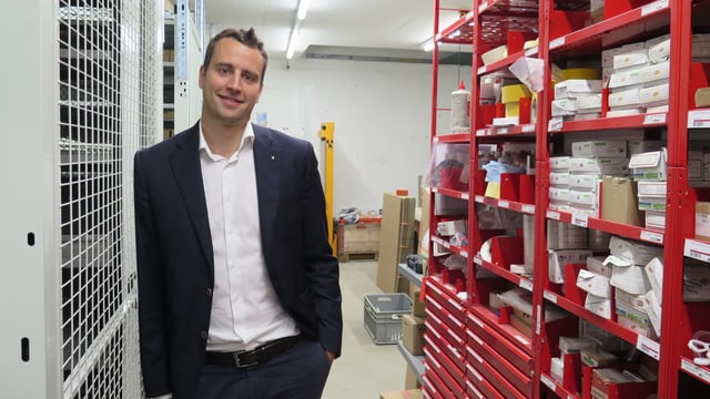 Ein Mann steht in einem Lager. Angelehnt gegen ein Gestell. Ein Mann steht in einem Lager. Angelehnt gegen ein Gestell.