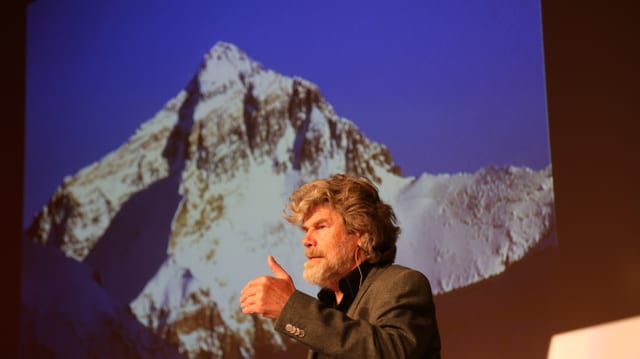 Reinhold Messner referescha davant in grond maletg dal Mount Everest. Reinhold Messner referescha davant in grond maletg dal Mount Everest.