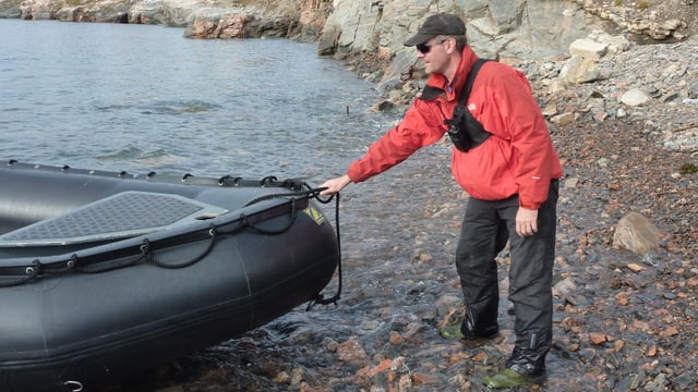 Reiseleiter zieht Schlauchboot ans Ufer. Reiseleiter zieht Schlauchboot ans Ufer.