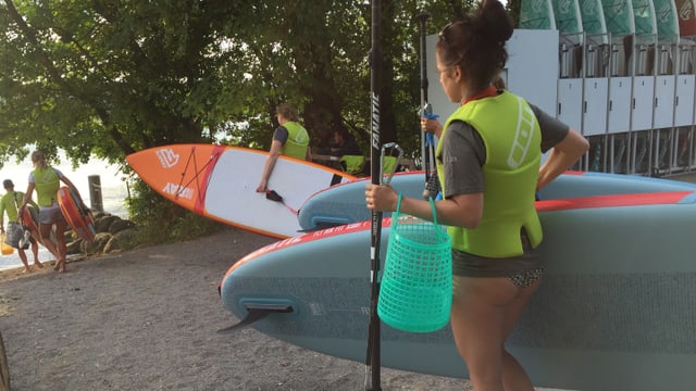Eine Frau läuft mit einem Stand Up Paddle zum See. Eine Frau läuft mit einem Stand Up Paddle zum See.