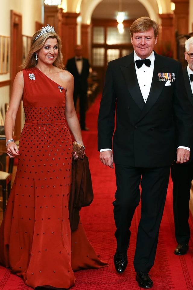 Máxima und Willem-Alexander in edler Robe. Maxima in einem langen rooten Ballkleid. Willem trägt einen schwarzen Nazug mit Orden. Máxima und Willem-Alexander in edler Robe. Maxima in einem langen rooten Ballkleid. Willem trägt einen schwarzen Nazug mit Orden.