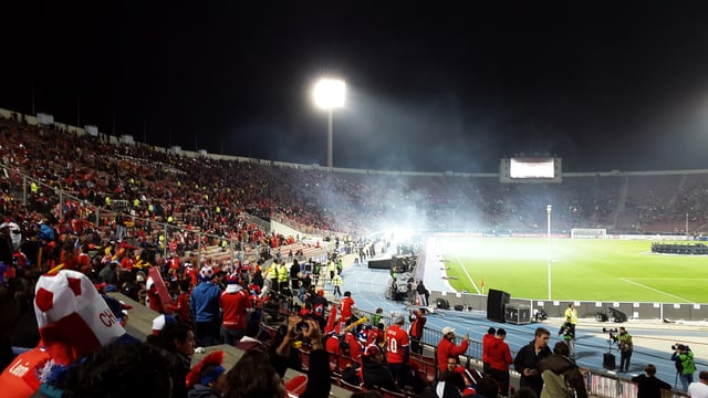 Blick in ein Fussballstadion bei Nacht mit rot gekleideten Fans. Blick in ein Fussballstadion bei Nacht mit rot gekleideten Fans.