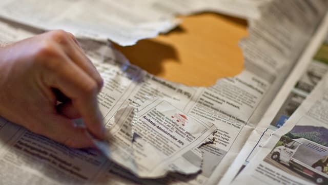 Aus einer Zeitung hat jemand ein Stelleninserat herausgerissen und hält es mit der einen Hand in die Kamera. Aus einer Zeitung hat jemand ein Stelleninserat herausgerissen und hält es mit der einen Hand in die Kamera.