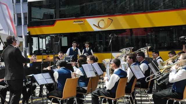 Ils musitcants da la Musica instrumentala Salouf Mon Stierva, che sunan sin sutgas da lenn davant in auto da posta mellen. Ils musitcants da la Musica instrumentala Salouf Mon Stierva, che sunan sin sutgas da lenn davant in auto da posta mellen.