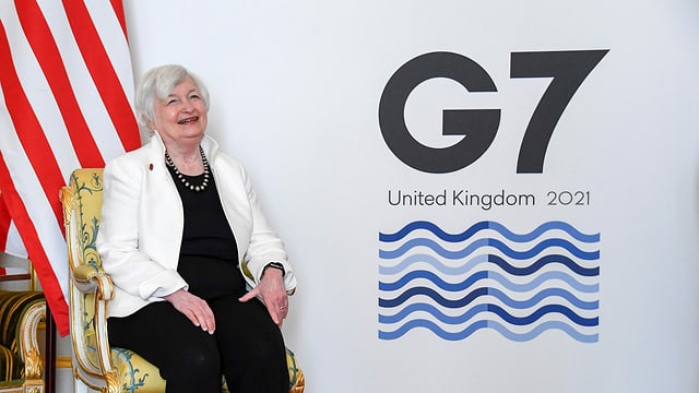 Frau, die lacht, vor einer US-Fahnen und dem Logo der G7. Frau, die lacht, vor einer US-Fahnen und dem Logo der G7.