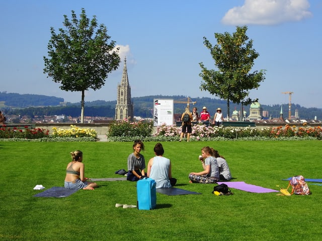 Die Menschen auf dem Rasen im Berner Rosengarten genissen die Sommersonne.