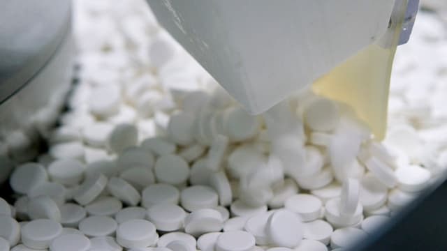 Weisse Pillen in Nahaufnahme in einer Fabrikationsmaschine Weisse Pillen in Nahaufnahme in einer Fabrikationsmaschine