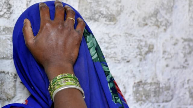 Eine Frau hat ihre blaue Sari über das Gesicht gezogen und hält die Hand an die Stirn. Eine Frau hat ihre blaue Sari über das Gesicht gezogen und hält die Hand an die Stirn.