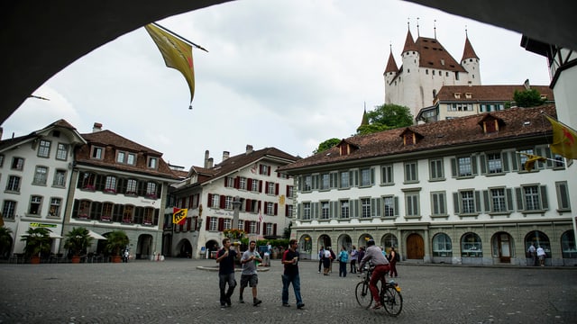 Stadtplatz mit Menschen darauf, im Hintergrund das Schloss Thun.
