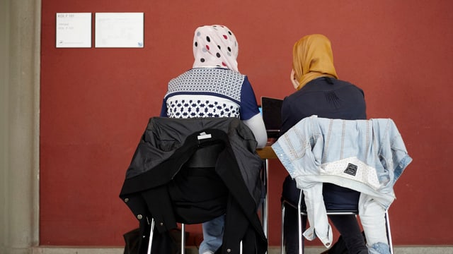 Symbolbild: Zwei Frauen mit Kopftuch sitzen auf Stühlen, mit dem Rücken gegen den Fotografen. Symbolbild: Zwei Frauen mit Kopftuch sitzen auf Stühlen, mit dem Rücken gegen den Fotografen.
