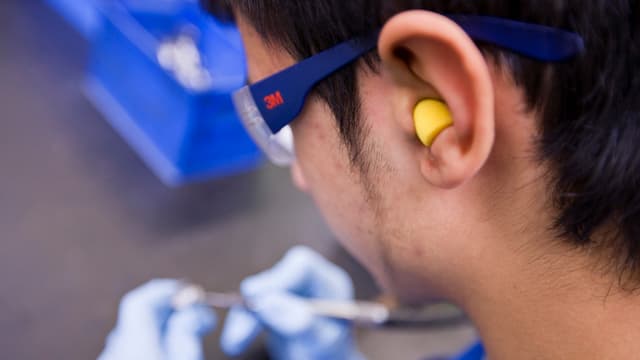 Mann mit Schutzbrille und Ohrenstöpsel bei der Arbeit Mann mit Schutzbrille und Ohrenstöpsel bei der Arbeit