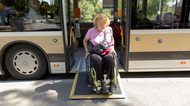 Frau mit Rollstuhl verlässt einen Linienbus Frau mit Rollstuhl verlässt einen Linienbus