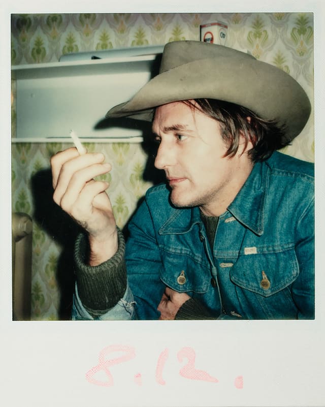 Ein Mann mit Cowboy-Hut und Jeans-Jacke hält eine Zigarette in der Hand. Ein Mann mit Cowboy-Hut und Jeans-Jacke hält eine Zigarette in der Hand.