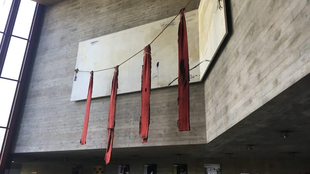 Vier rote Tücher hängen von einem Seil vor einer Leinwand Vier rote Tücher hängen von einem Seil vor einer Leinwand