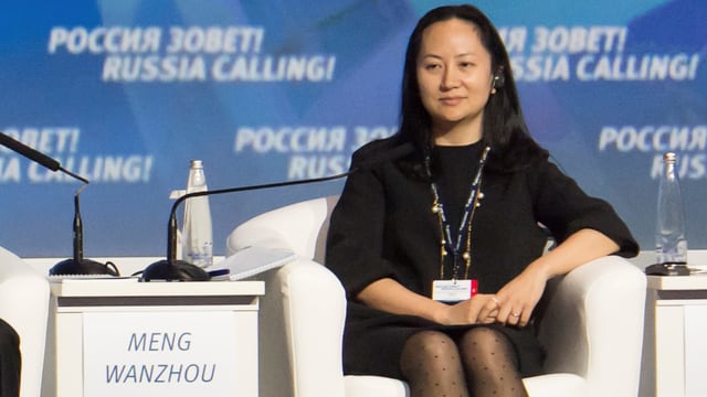Meng Wanzhou auf einer Bühne sitzend auf einem weissen Sessel. Meng Wanzhou auf einer Bühne sitzend auf einem weissen Sessel.